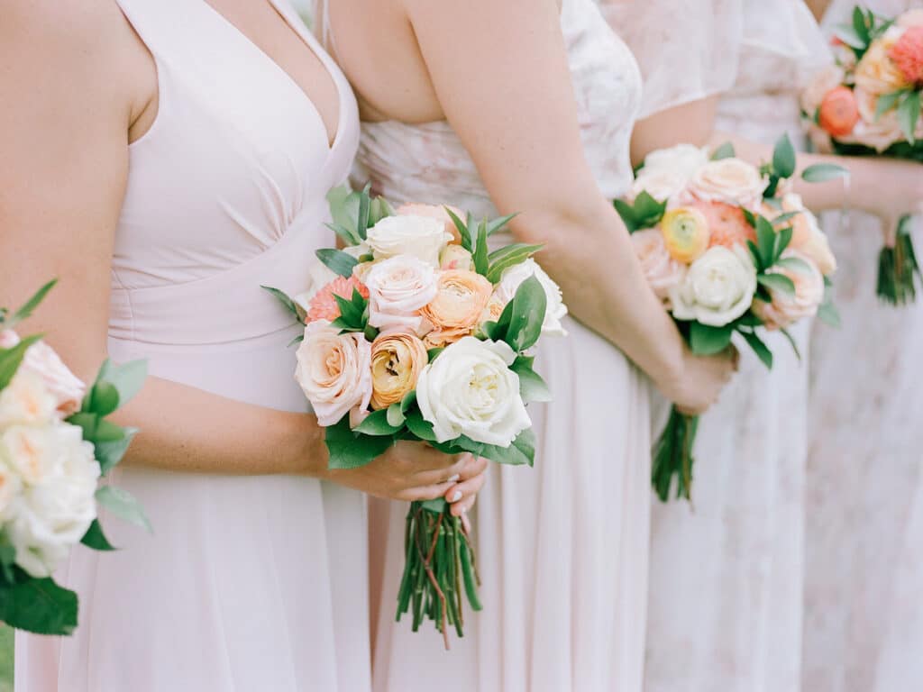 A group of bridesmaids in light pink dresses lined up and holding bouquets.