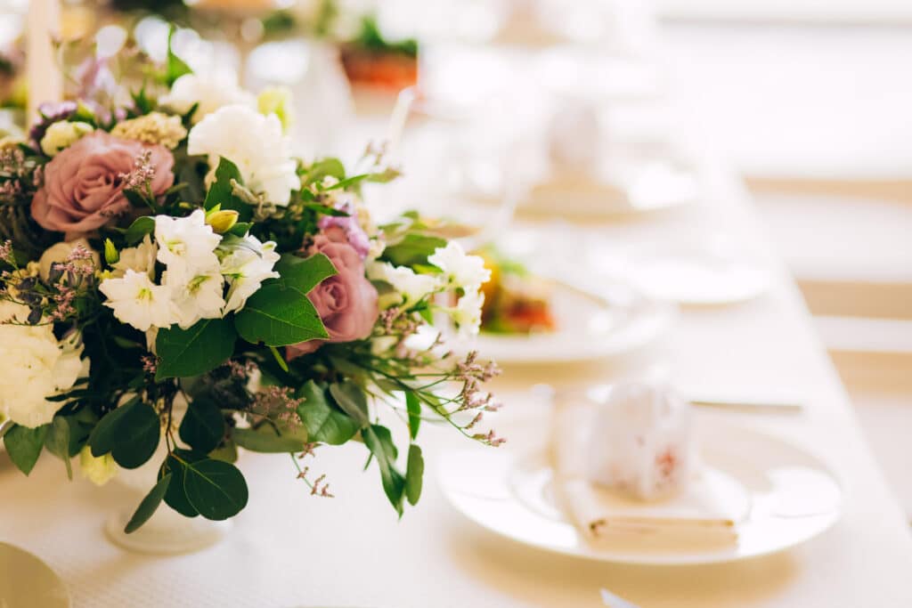 Gorgeous luxury wedding table arrangement, floral centerpiece close up. The table is served with cutlery, crockery and covered with a tablecloth. Wedding party decoration with pink and white flowers.
