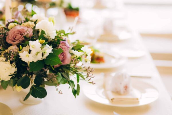 Gorgeous luxury wedding table arrangement, floral centerpiece close up. The table is served with cutlery, crockery and covered with a tablecloth. Wedding party decoration with pink and white flowers. Gorgeous luxury wedding table arrangement, floral centerpiece close up. The table is served with cutlery, crockery and covered with a tablecloth. Wedding party decoration with pink and white flowers.