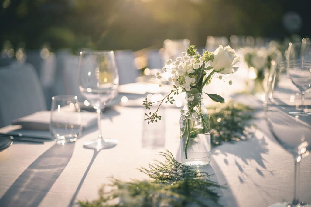 An elegant table set with white place settings and white centerpieces.