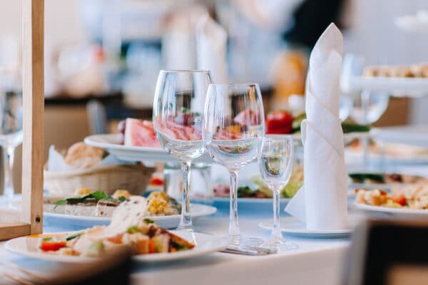 AdobeStock_379364773_web An elegant table setting, with food, wine glasses and decorative napkins.