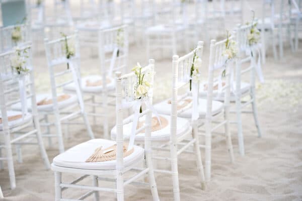 AdobeStock_489866831_web Elegant place settings with tulle and white roses on the chairs.