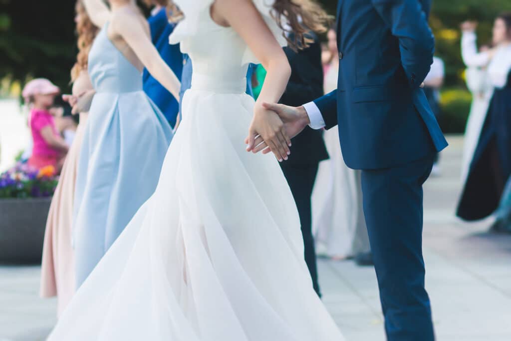 A group of teens in dresses and suits walking and holding hands