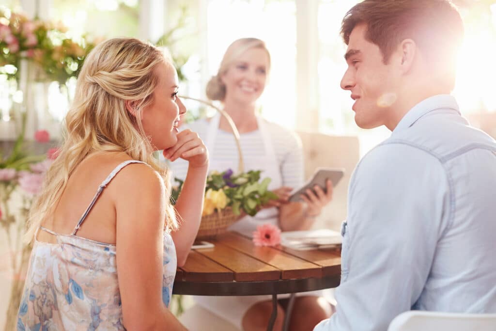 A man and woman smiling at each other while sitting across the table from an event planner.