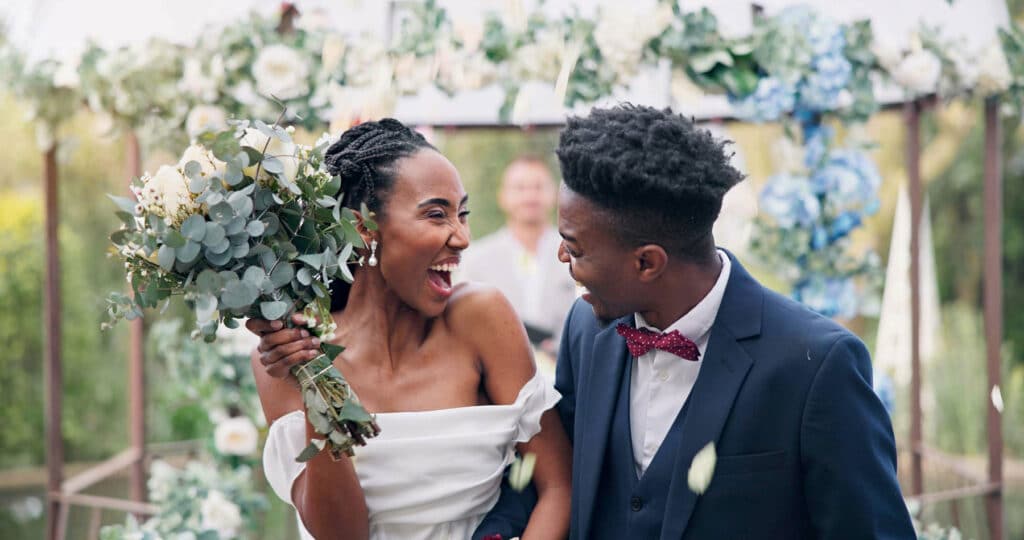 Bride and groom looking at each other and giving excited open-mouthed smiles at each other as they walk back up the aisle at the end of the wedding ceremony.
