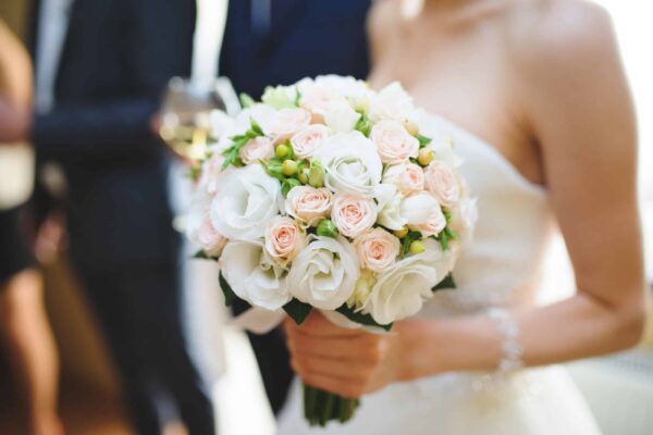 Wedding Bouquet A bride in white clutching a bouquet of white, pink and yellow flowers.