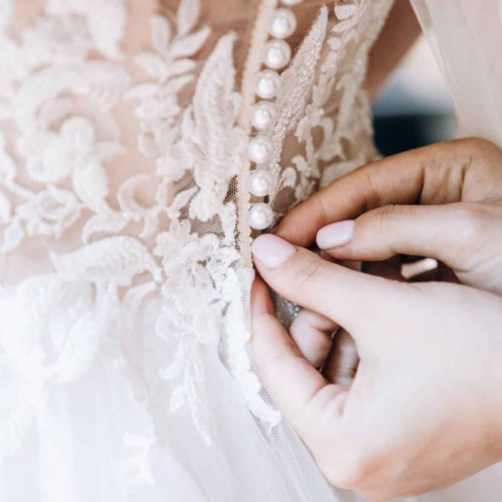 bride getting buttons fastened on dress